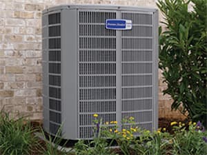 Residential AC Installation in North Texas American Standard air conditioning unit installed outside a brick home with landscaping